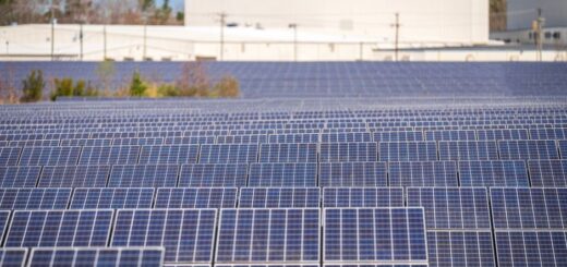 Aerial view of a solar farm with drones inspecting solar panels and cabling for maintenance.